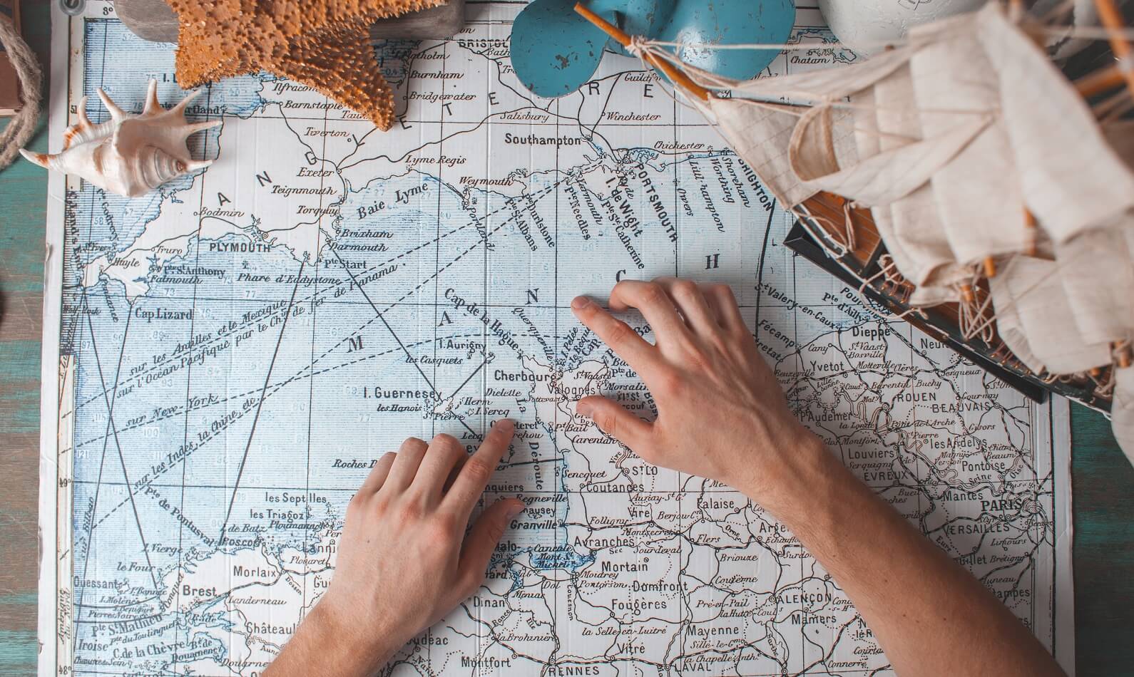 mans-hand-on-map-on-desk-with-traveller-attributes-PCREGE6.jpg